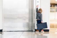 Copilul cu servieta arată spre un lift.