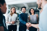 Angajații CANCOM Austria întâmpină noii membri ai echipei cu o strângere de mână cooperantă.