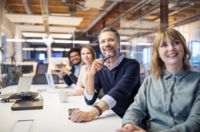 Grup de angajați care stau într-un birou și lucrează împreună la o soluție modernă de comunicare.