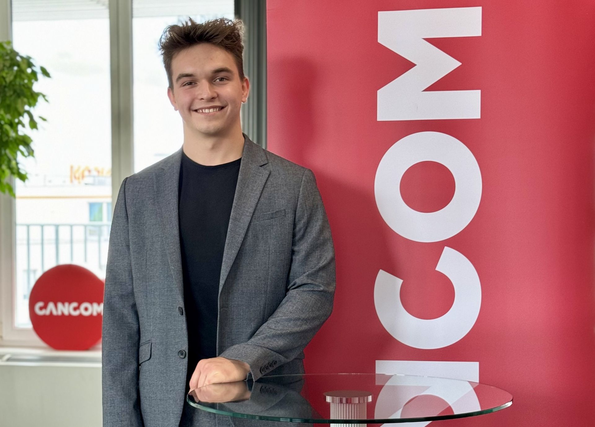 Un bărbat în costum stă zâmbind în fața unui panou în birou.