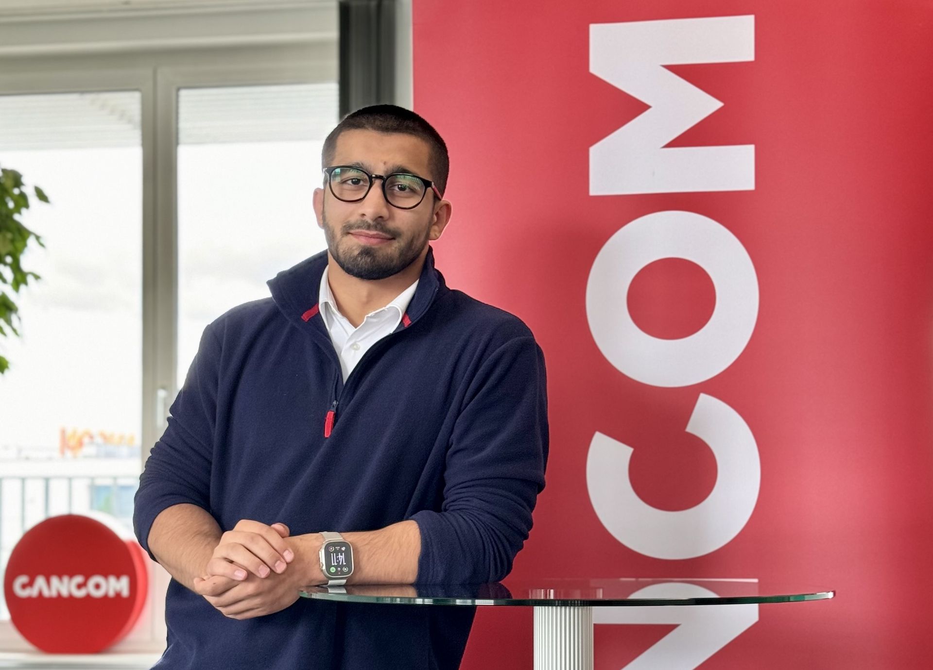 Un bărbat stă în fața unui semn roșu, care corespunde contextului programului de carieră JumpIN pentru absolvenții HTL/HTBLA la CANCOM Austria.