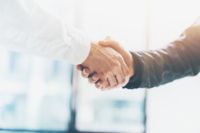 Oamenii de afaceri prezenți la CANCOM Austria își strâng mâinile în semn de încredere și cooperare.